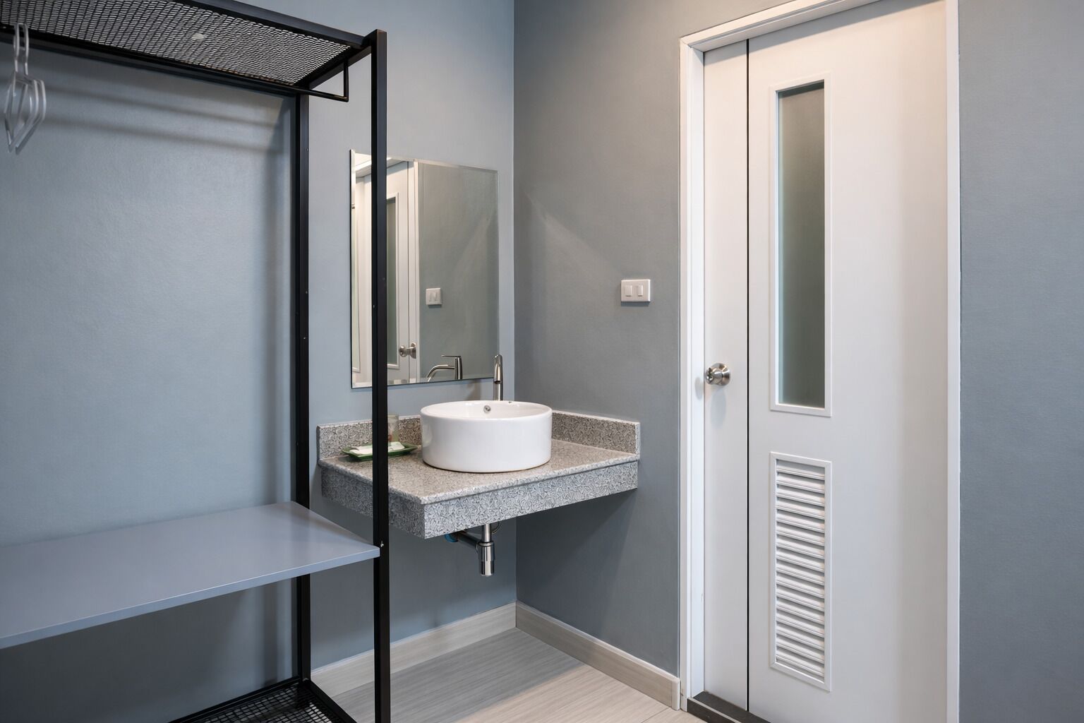 Un baño moderno con un lavamanos blanco, un espejo y una puerta.
