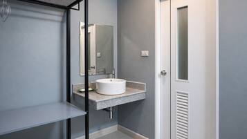 Un baño moderno con un lavamanos blanco, un espejo y una puerta.