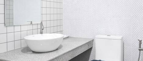 A bathroom with a white sink, a toilet, and a shower area.