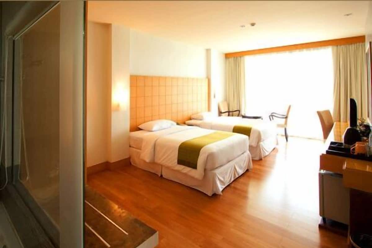 Une chambre d’hôtel avec deux lits, un bureau et une chaise.