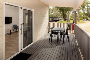 A covered outdoor area with a table and chairs, a television, and a sliding glass door leading to an interior space.