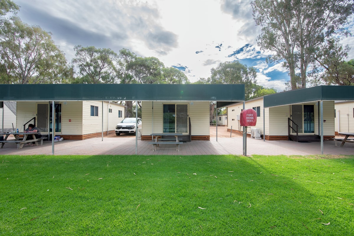 A row of mobile homes with a covered patio area, outdoor seating, and a fire hydrant.