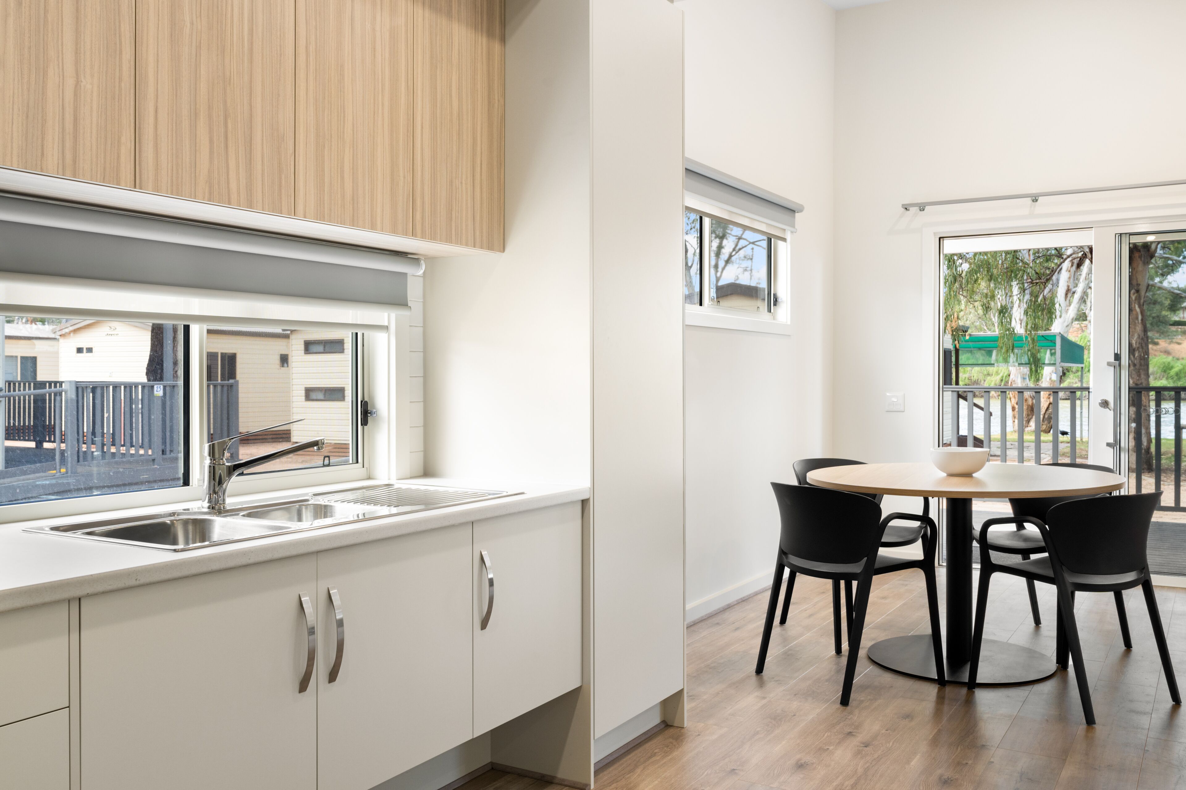 A modern kitchen with a sink, cabinets, and a dining area with a table and chairs.