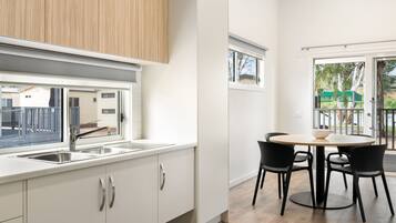 A modern kitchen with a sink, cabinets, and a dining area with a table and chairs.