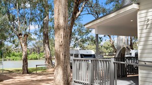 A covered outdoor area with a wooden deck, a metal railing, and a white building with a garage. - Echo Holiday Parks - Renmark (Renmark)