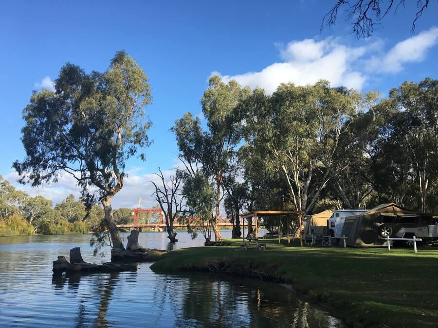 A campsite with a lake, trees, and a bridge in the background.
