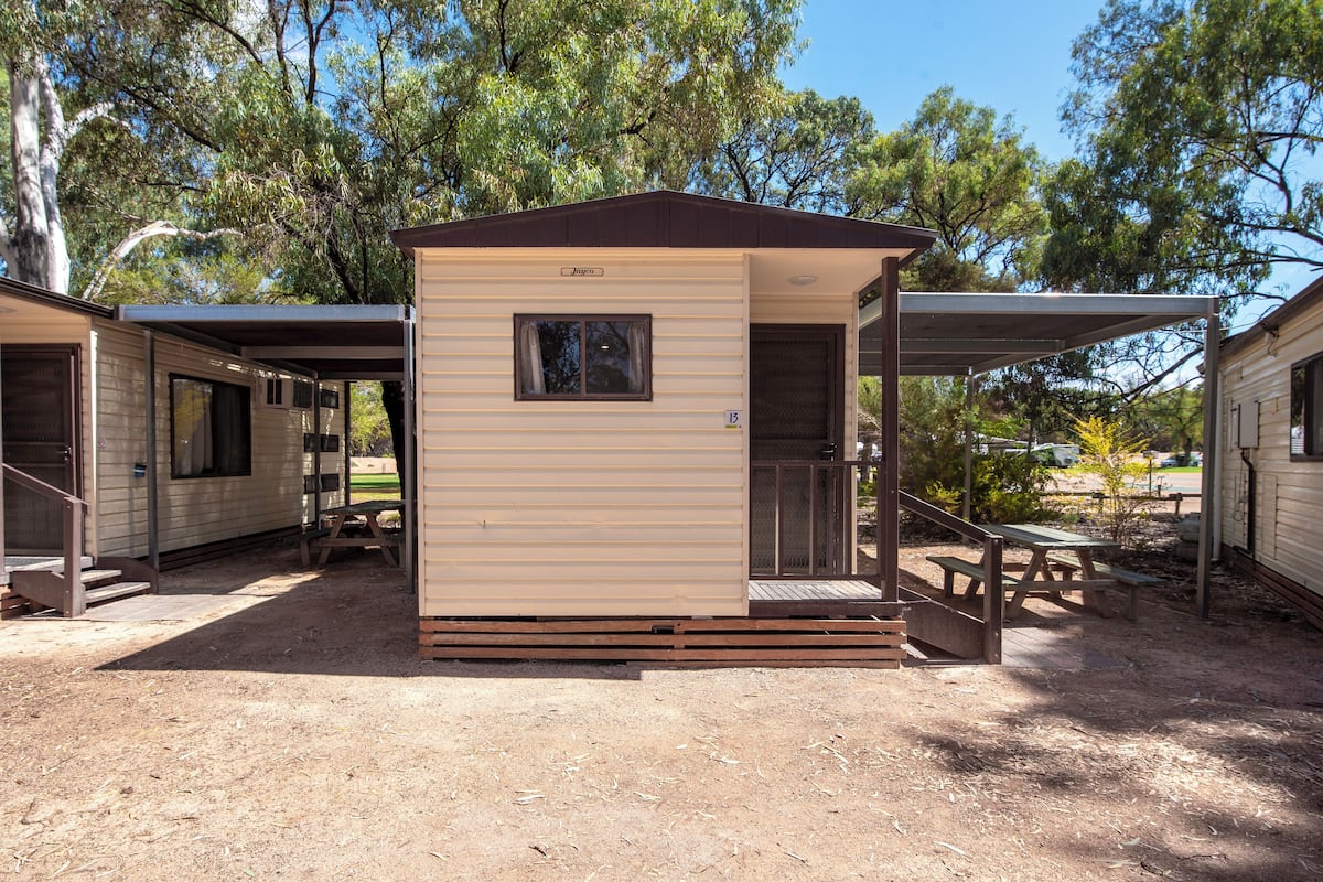 A small, single-story mobile home with a covered porch and a picnic table.