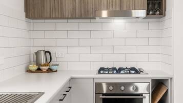 A modern kitchen with white subway tiles, stainless steel appliances, and wooden cabinets.