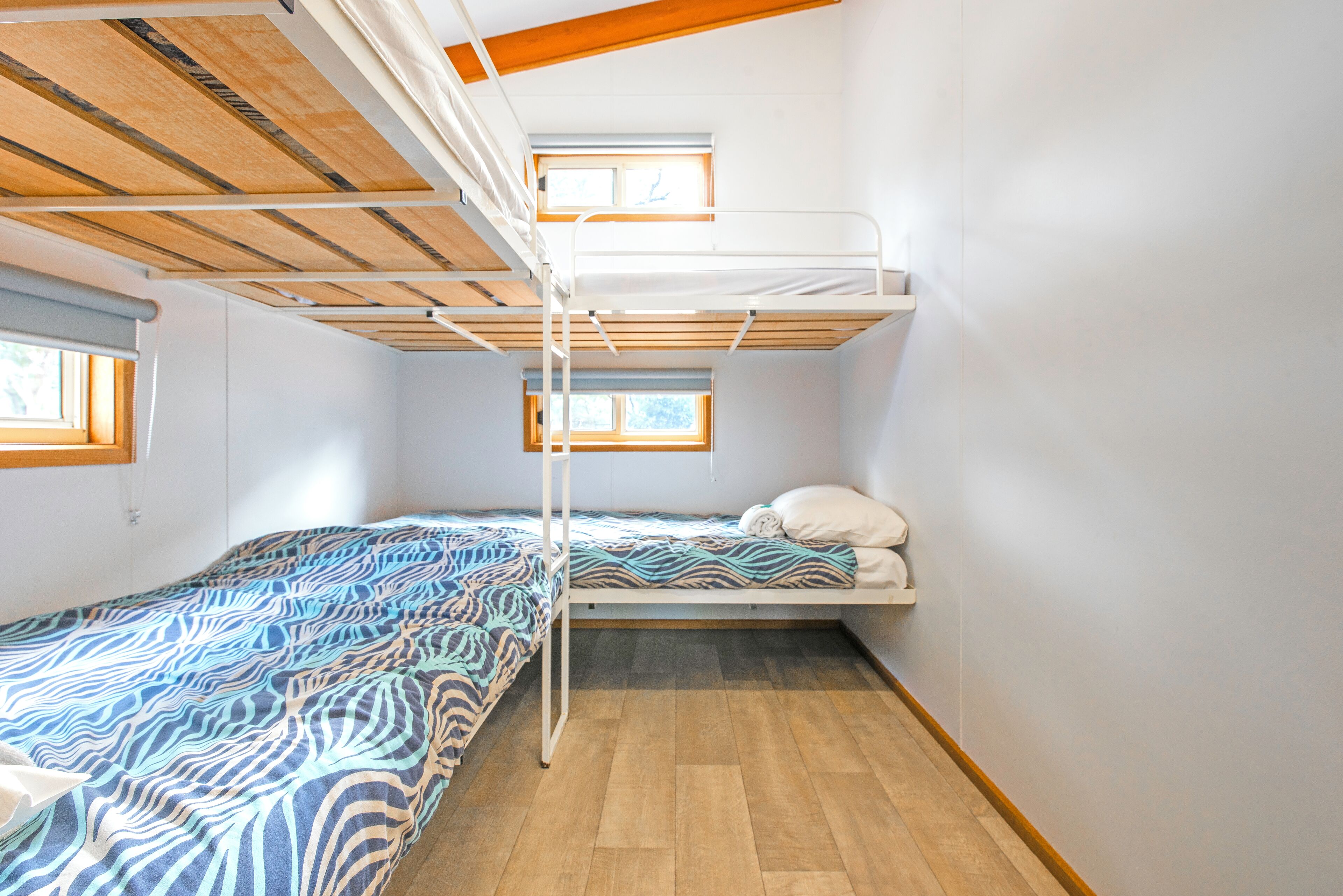 Un dormitorio con literas, una ventana y una colcha estampada.
