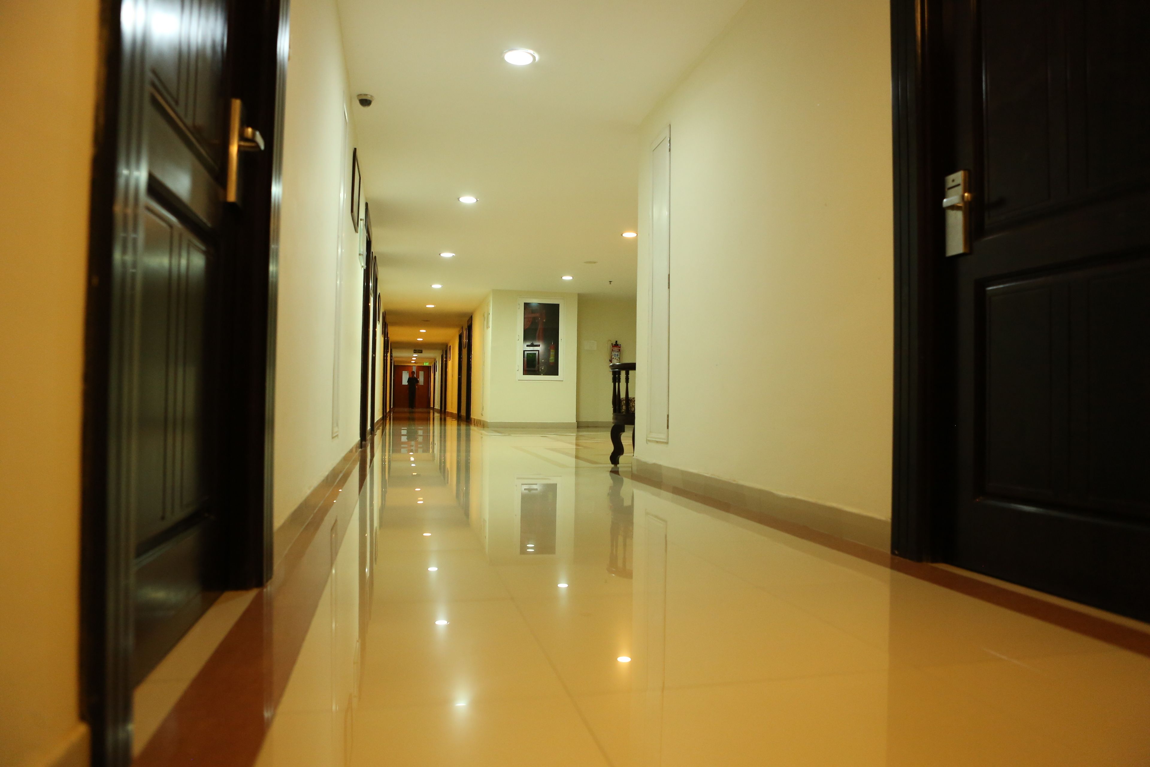 A long, well-lit hallway with a shiny floor, leading to a door at the end.