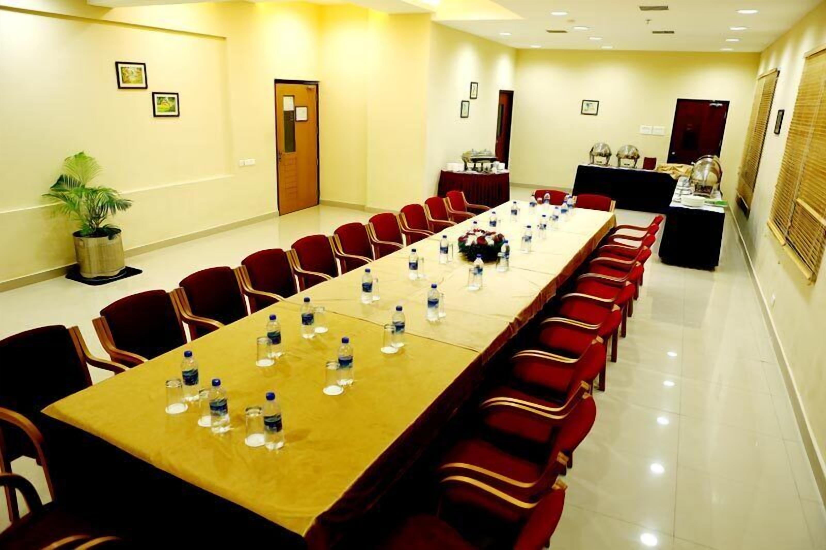 A conference room with a long table, red chairs, and water bottles.