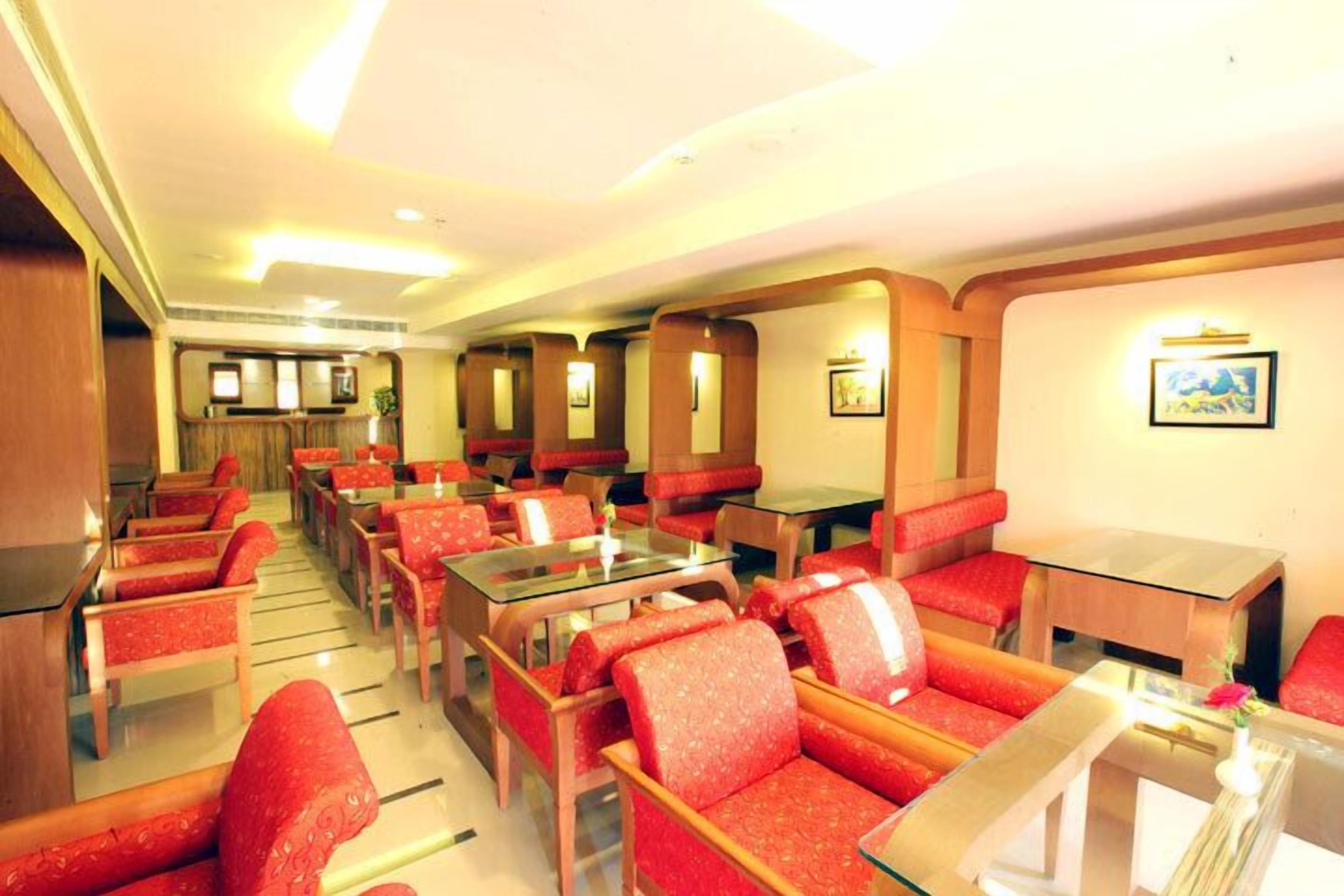 A hotel dining area with red upholstered booths and glass-top tables.