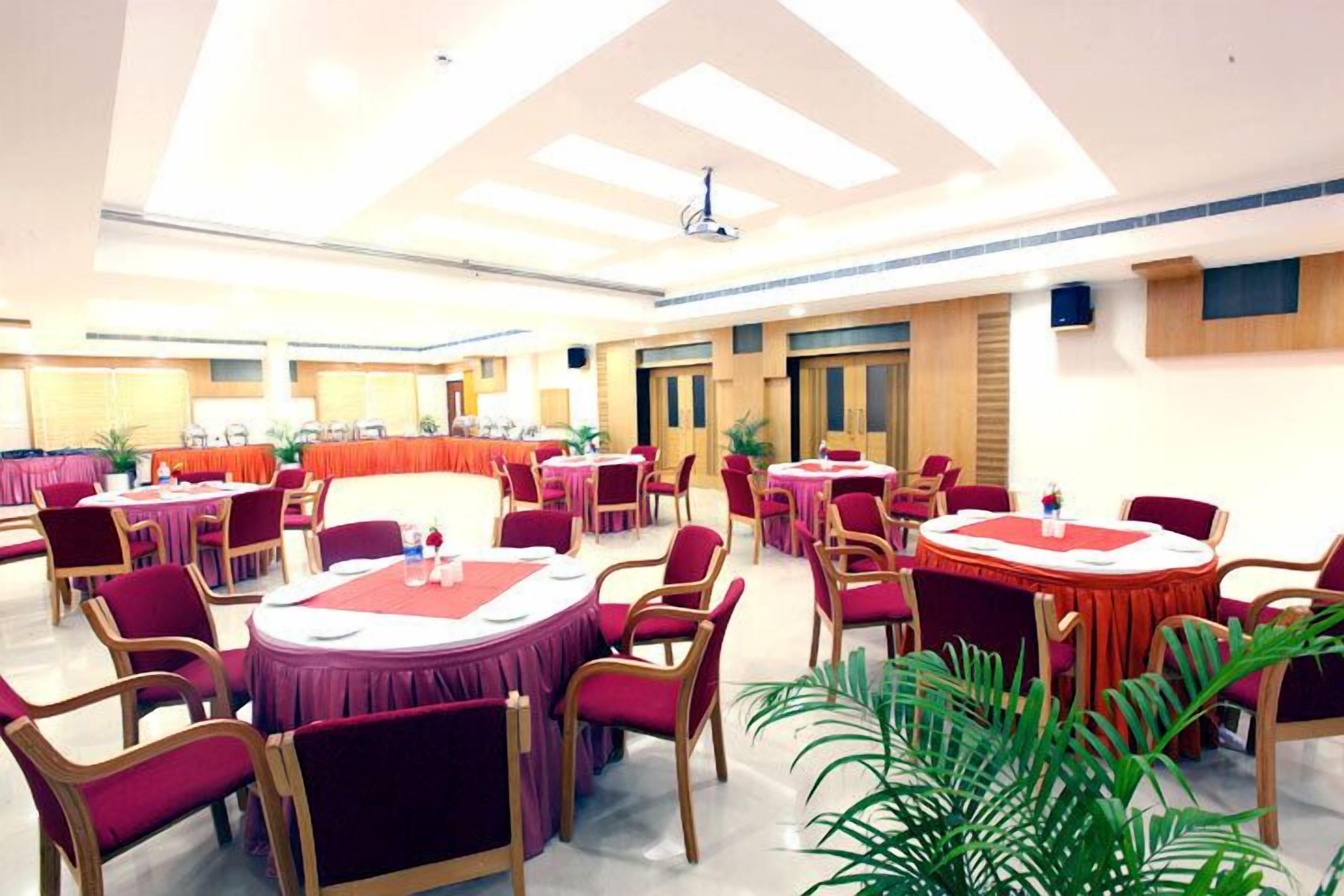 Un amplio salón de banquetes con mesas y sillas redondas, un techo alto con tragaluces y un diseño interior moderno.