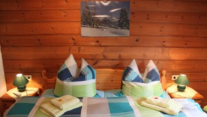 Un dormitorio de cabaña de madera con cama, almohadas y mesita de noche con lámpara.
