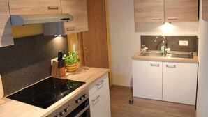 Una cocina con armarios de madera, estufa, lavabo y encimera con una planta.