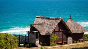 Ein Strandgrundstück mit strohgedeckten Hütten mit Blick auf den Ozean.
