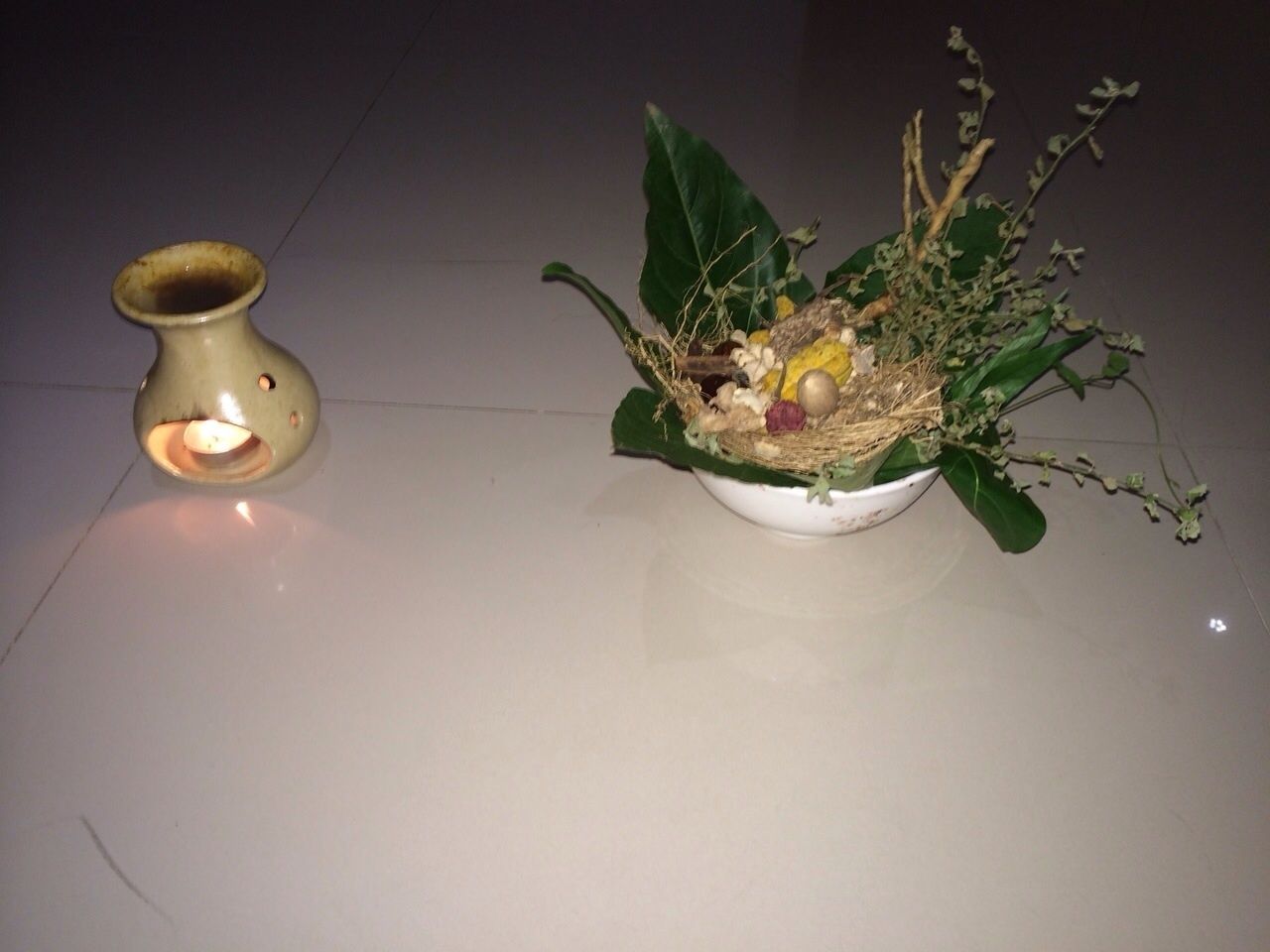 A small, rustic vase with a candle on a white surface.