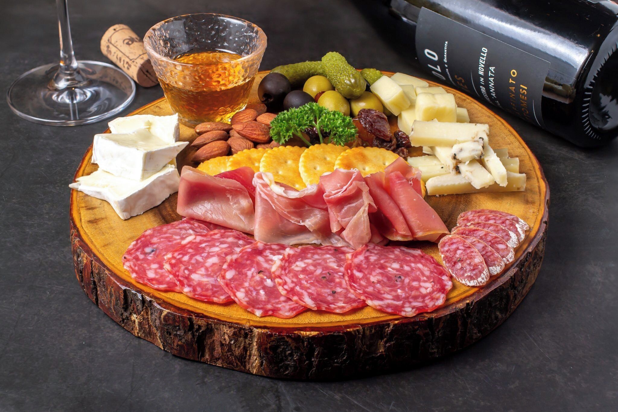 A charcuterie board with various meats, cheeses, nuts, and olives.