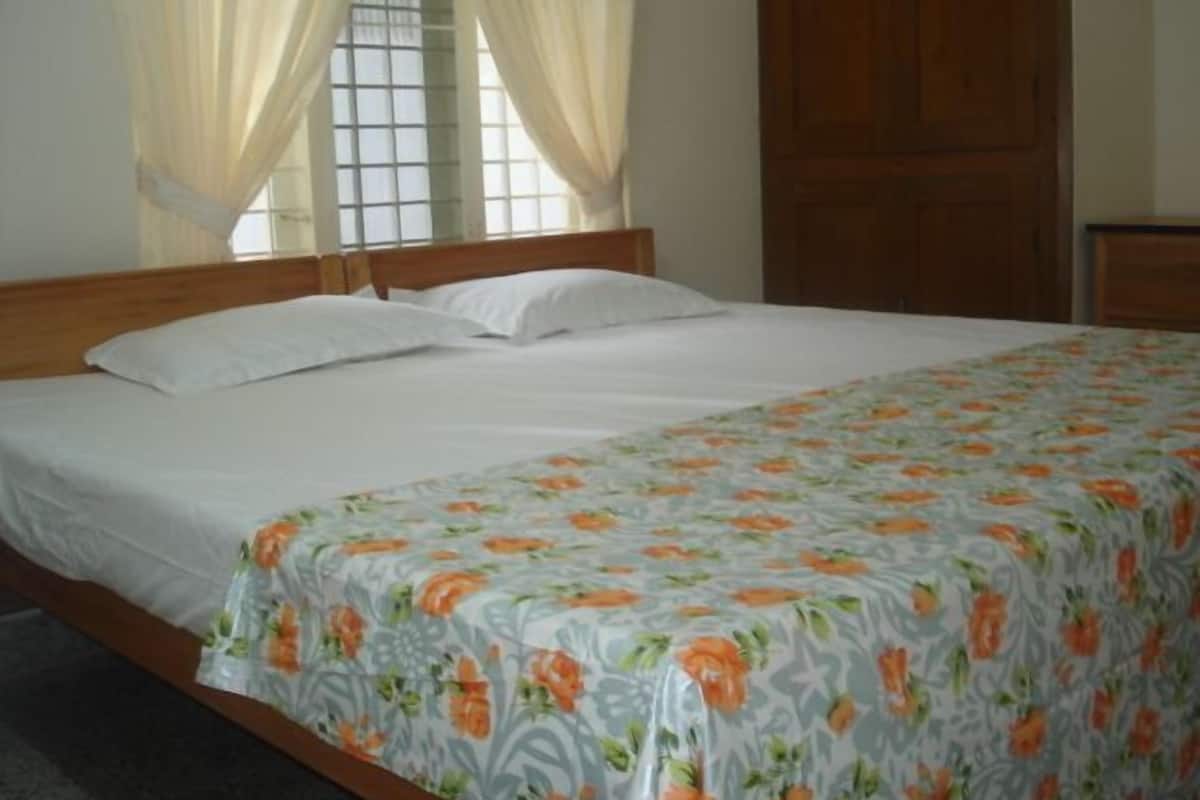 A bedroom with a bed, curtains, and a wooden wardrobe.