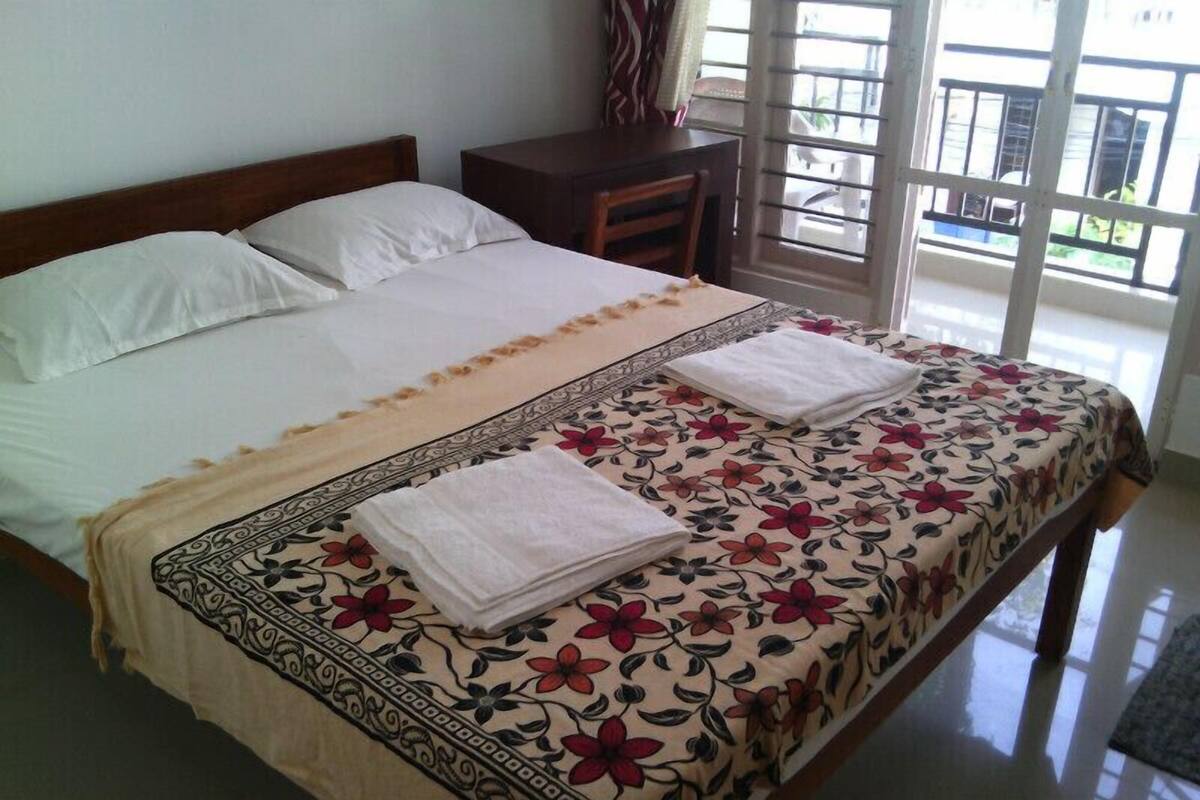 A neatly made bed with a floral bedspread and two folded towels on the side.