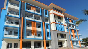A multi-story hotel with a modern design, featuring balconies on each floor, a central courtyard, and a parking area in front. - Trang Grand Mansion (Trang)