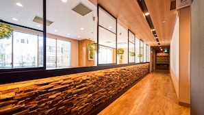 Een modern interieur met een stenen muur, houten plafond en grote ramen.