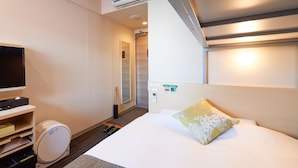 Een hotelkamer met een bed, een televisie, een minibars en een badkamedeur.