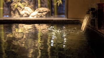A water feature with a bamboo backdrop and a stone structure.