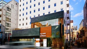 Een modern hotel met een witte gevel, meerdere ramen en een restaurant genaamd 'Lohas' op de begane grond.