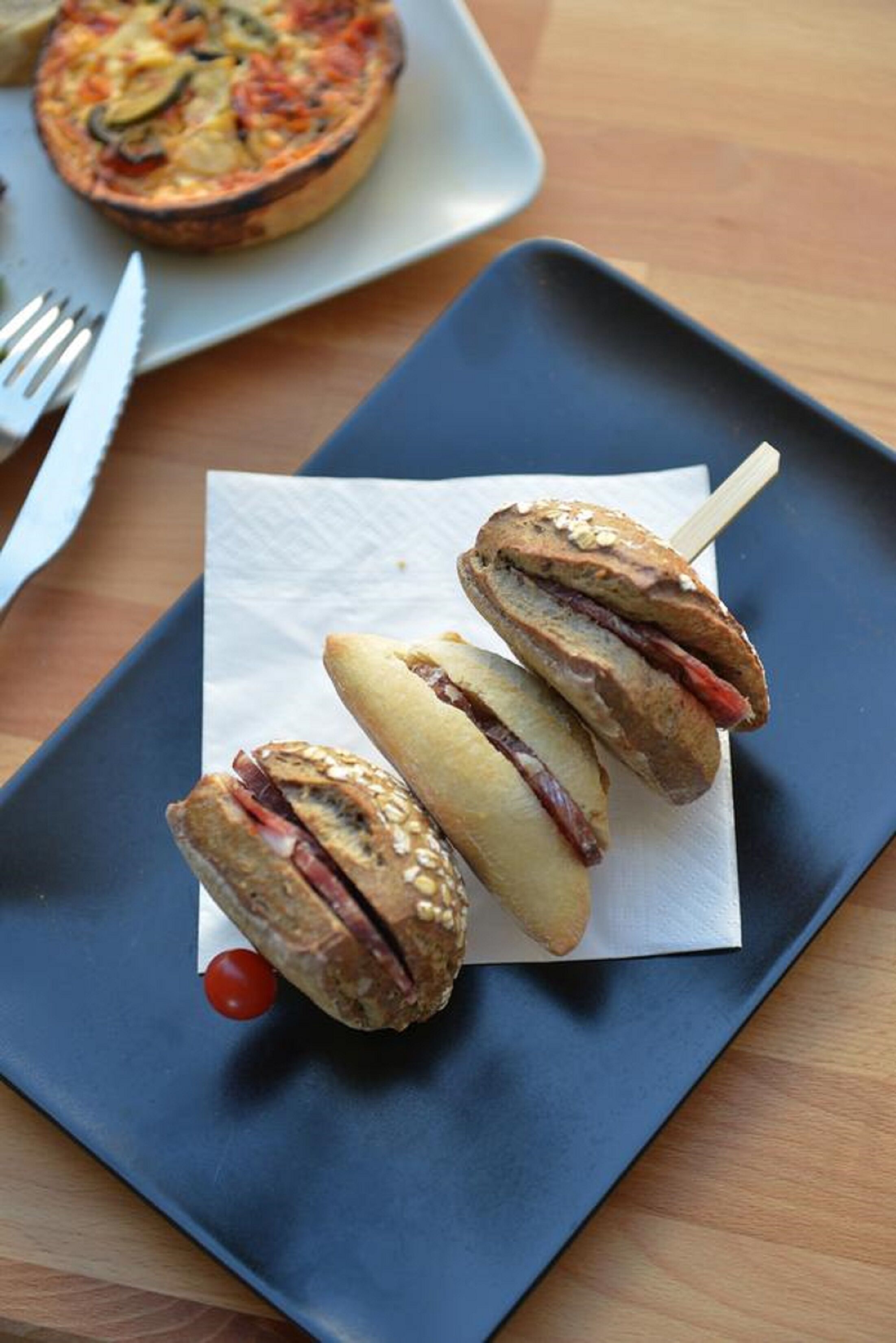 Un plato con tres sándwiches sobre una servilleta.