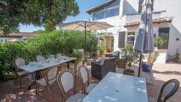 An outdoor patio with tables and chairs, surrounded by greenery and potted plants.