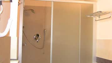 A bathroom with a glass-enclosed shower, a sink, and a towel rack.