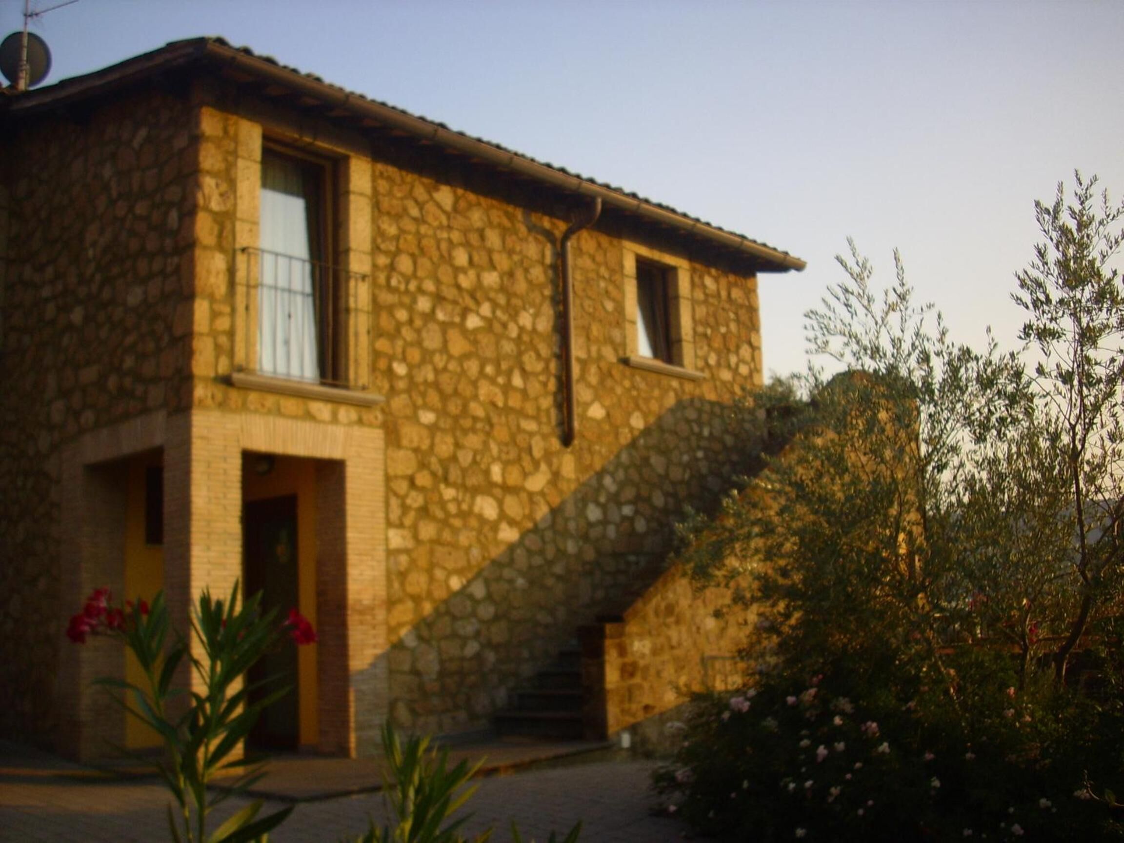 Una casa in pietra con una scala che conduce all'ingresso, immersa nel verde.