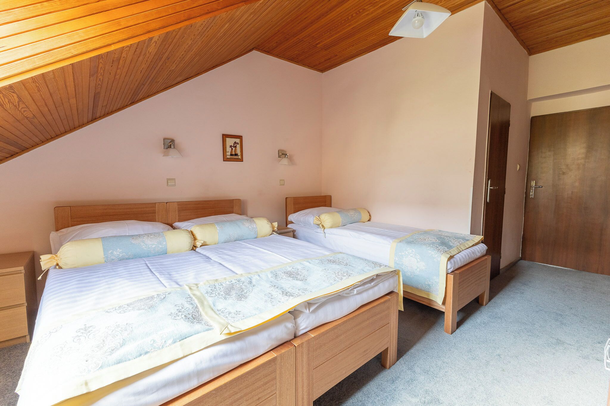 A bedroom with two wooden beds, a wooden ceiling, and a door.