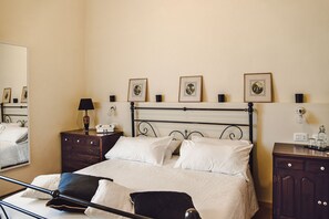 A neatly arranged bedroom with a bed, bedside tables, a mirror, and framed pictures on the wall. - Masseria Ciavolich (Loreto Aprutino)