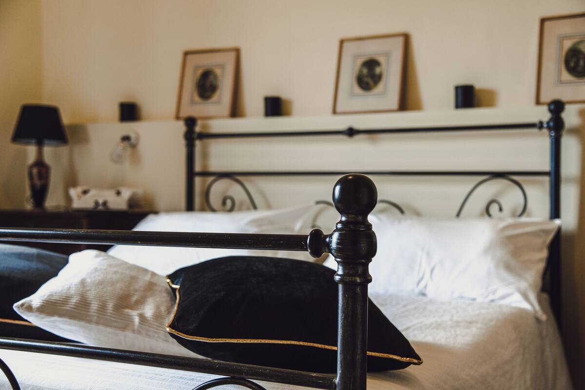 A bed with a metal frame, white bedding, and a black pillow.