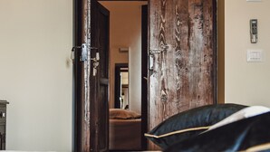 Une chambre d’hôtel avec une porte en bois, un lit avec une literie blanche et un oreiller.