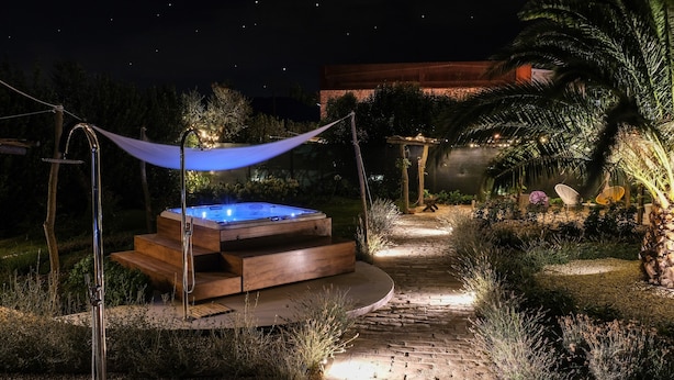 Un bain à remous dans un jardin, la nuit, sous un ciel étoilé.