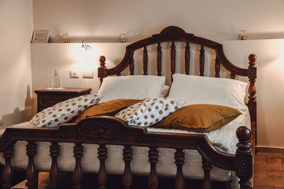 A wooden bed with a headboard, white bedding, and patterned pillows.