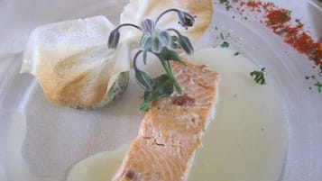 Une assiette avec du saumon, une fleur et quelques herbes aromatiques.
