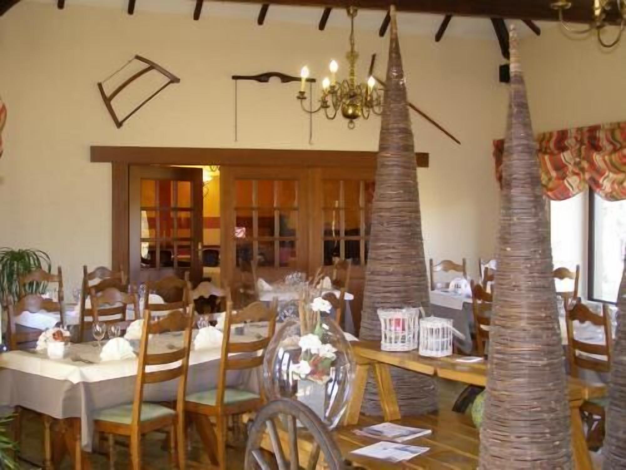 A dining area with wooden tables and chairs, a chandelier, and decorative palm trees.