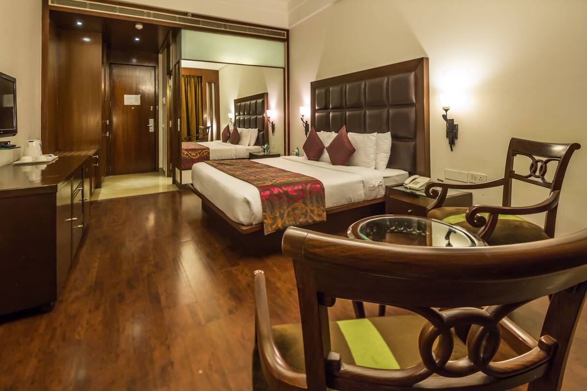 Una habitación de hotel con cama, escritorio, silla y espejo.