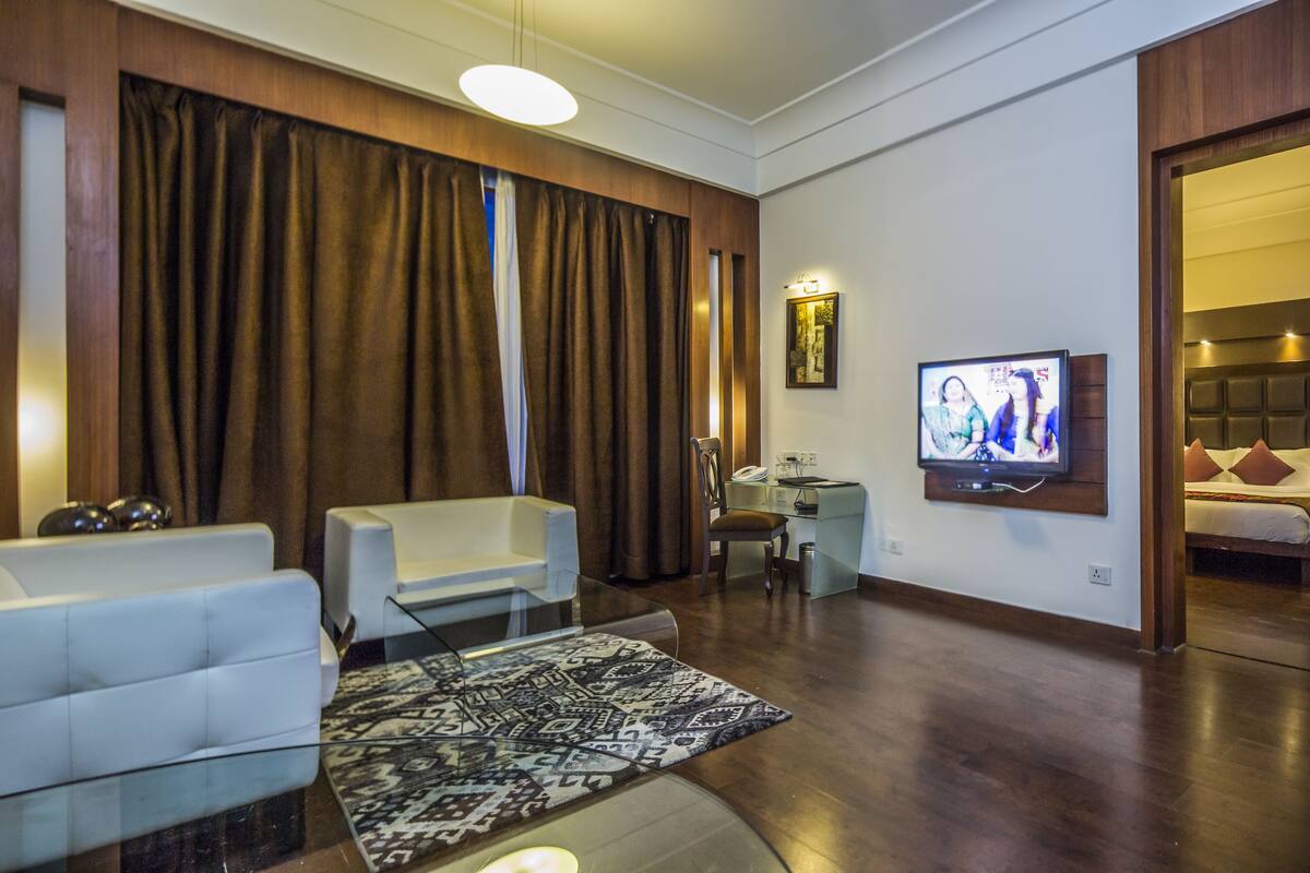 Una sala de estar moderna con un sofá, una mesa de centro de vidrio, un televisor y una alfombra estampada.