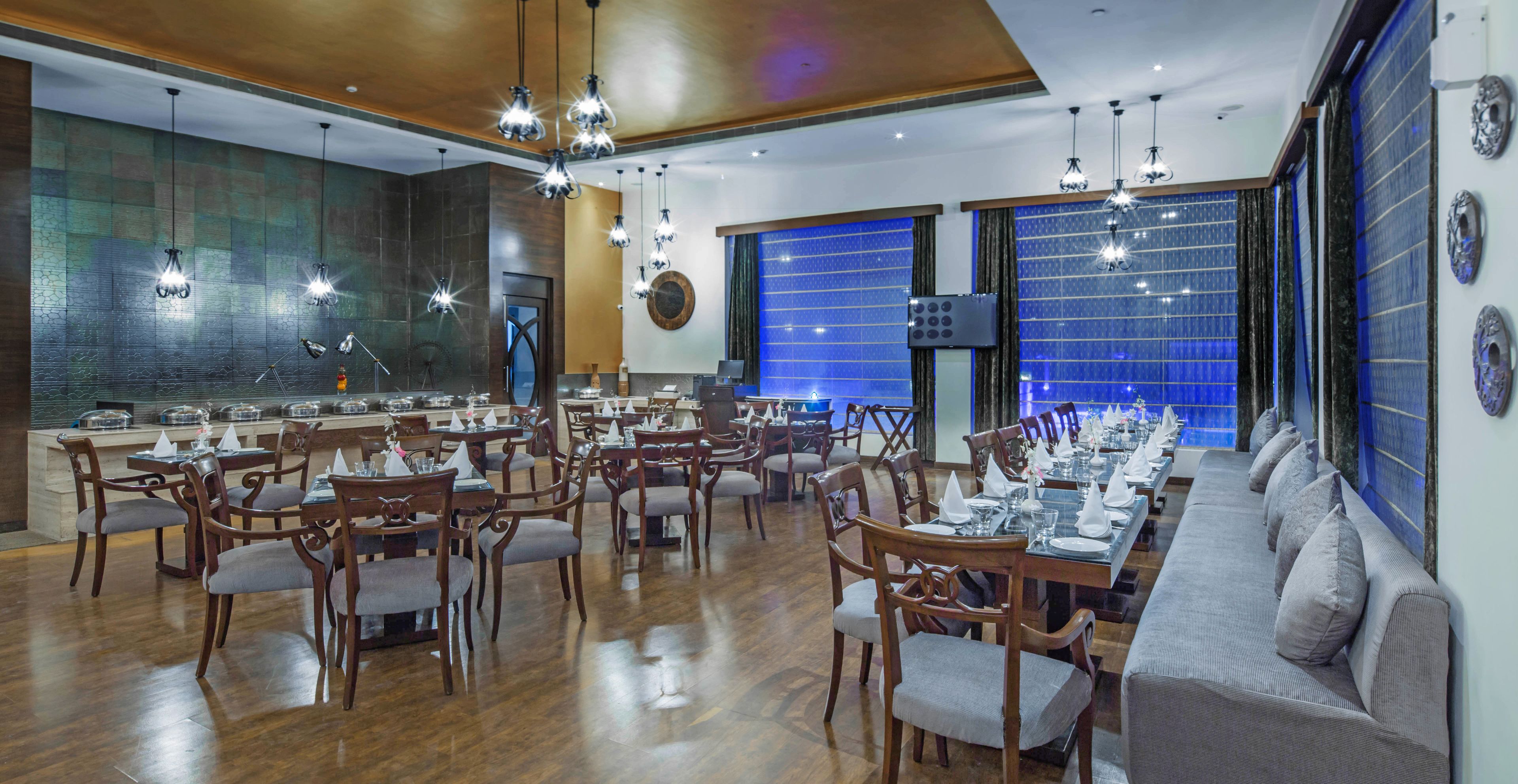 A spacious dining area with wooden tables and chairs, a long counter, and a blue patterned wall.