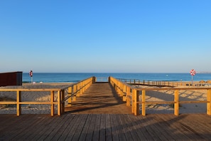 A wooden boardwalk leading to a beach with a lifebuoy sign and a no swimming sign. - Pestana Alvor South Beach, Premium Suite Hotel (PortimĂŁo)