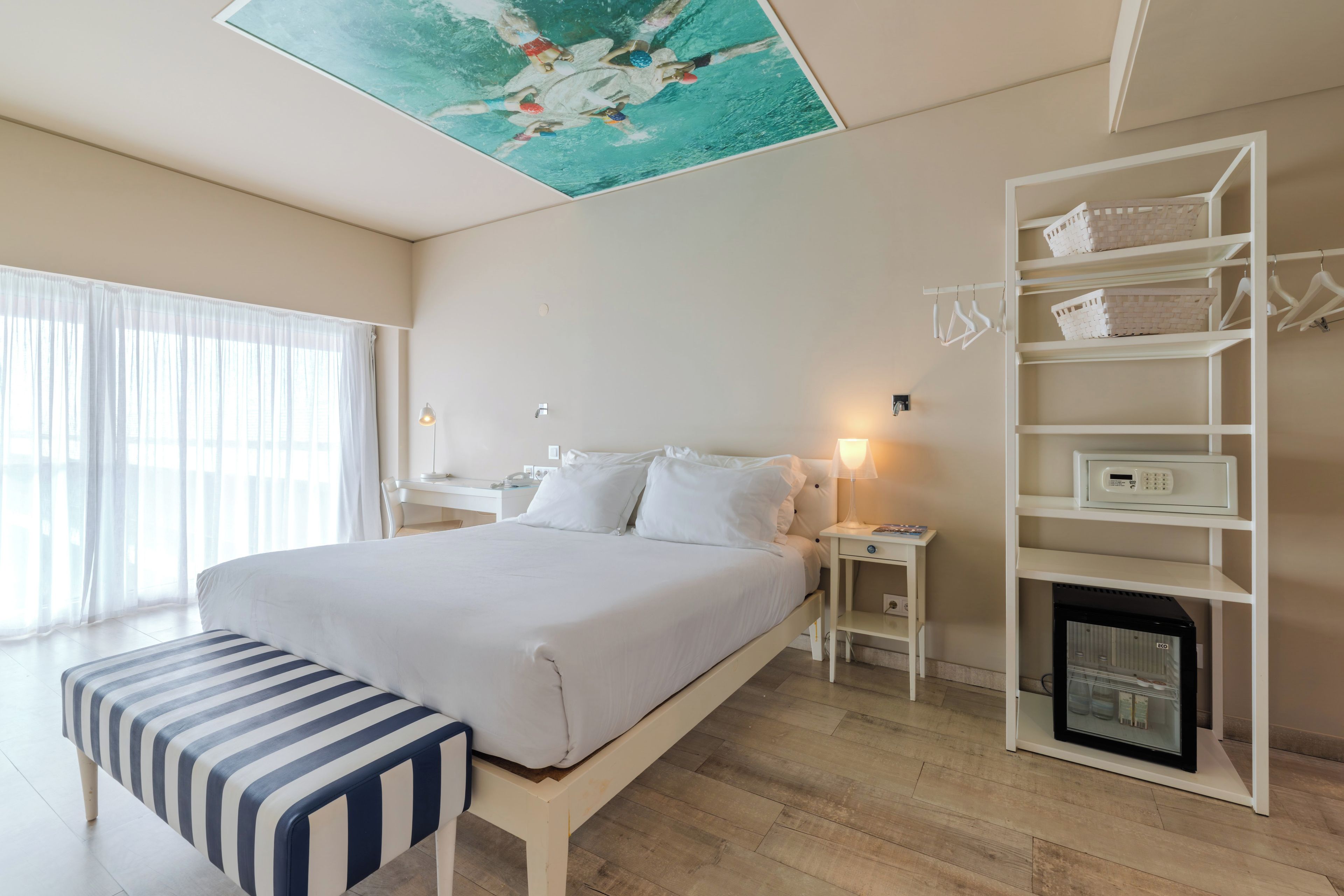 A hotel room with a bed, bedside tables, a bench, a wardrobe, and a fireplace.