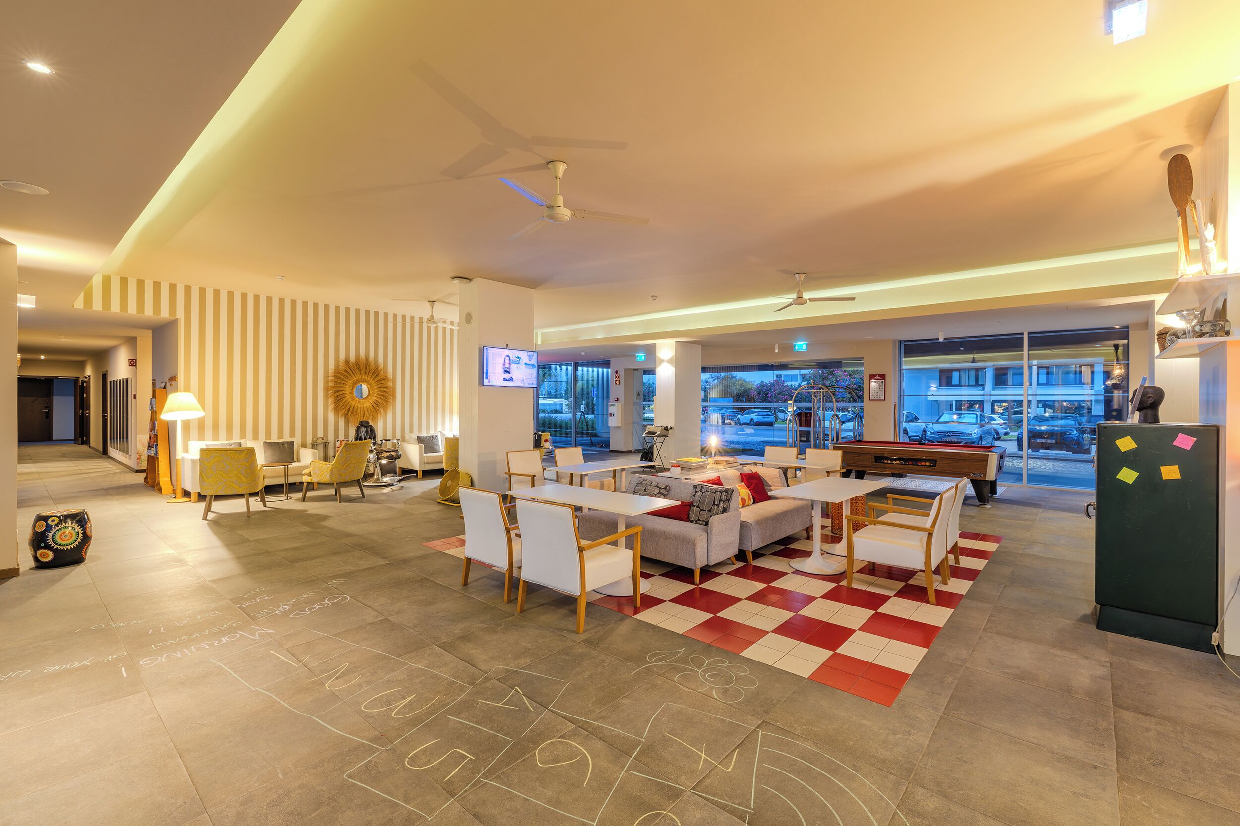 A modern hotel lobby with a checkered floor, seating area, and a pool table.