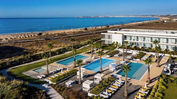 Un resort con varias piscinas, tumbonas y vistas a la playa.