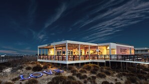 Une propriété située au bord de l’eau, dotée d’une structure entièrement vitrée, d’une terrasse et du mot « AMOUR » bien visible au premier plan.