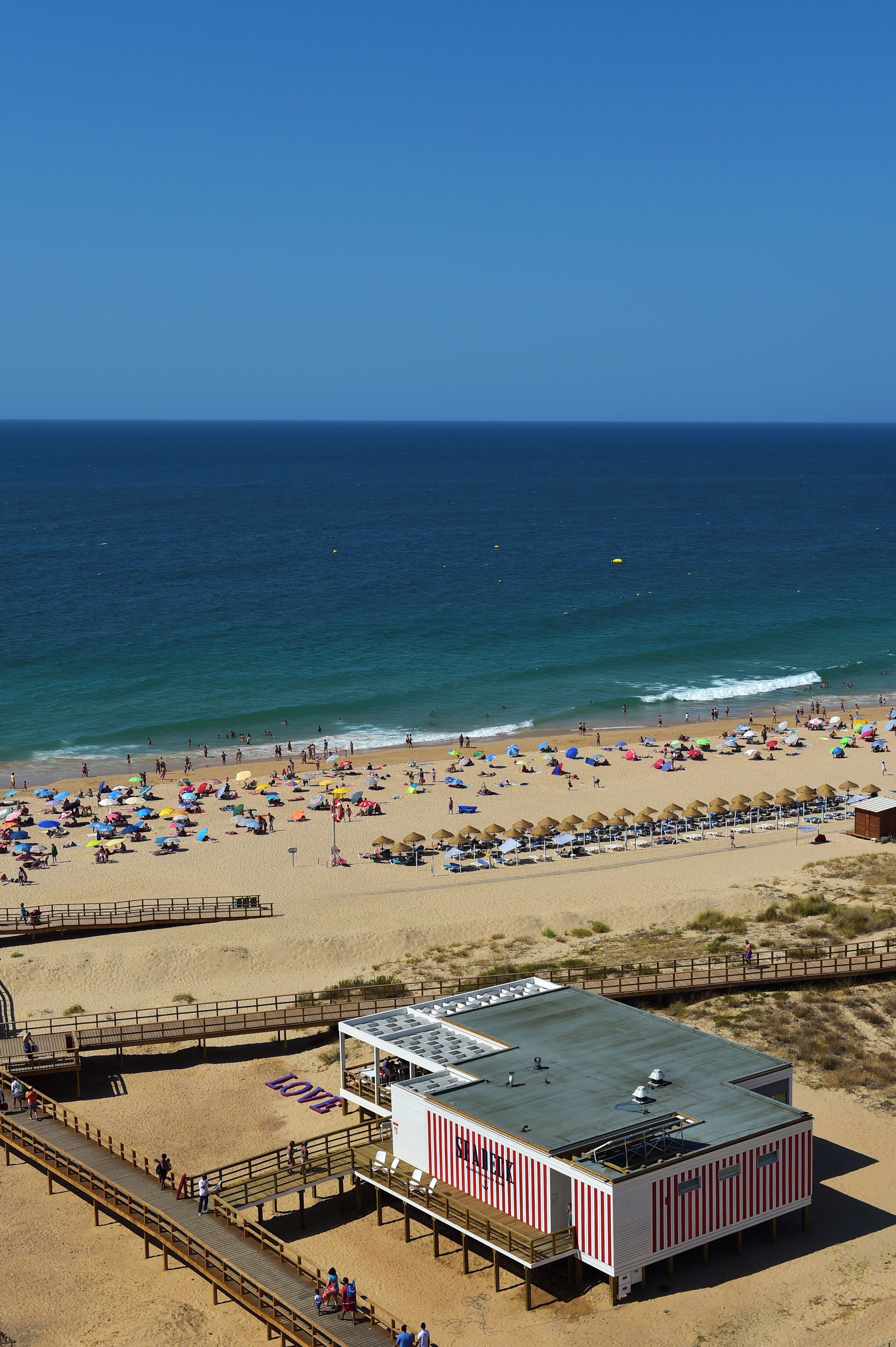 Una playa con una torre de salvavidas, un paseo marítimo y un edificio con la palabra 'LOVE' escrita.